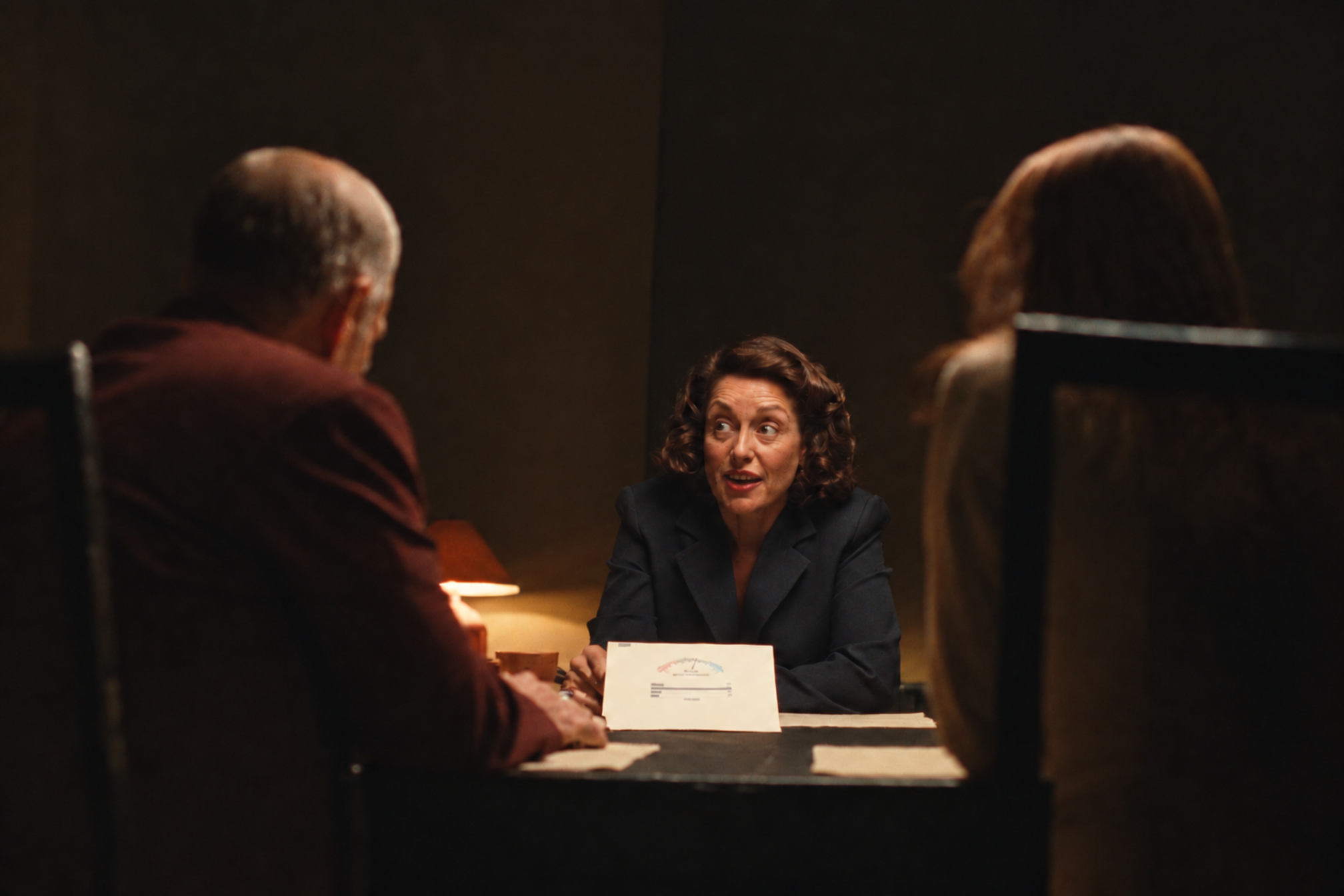 Illustrative scene, generated: an agent mid-sentence at a homeowner couple’s table, a one-page market report between them